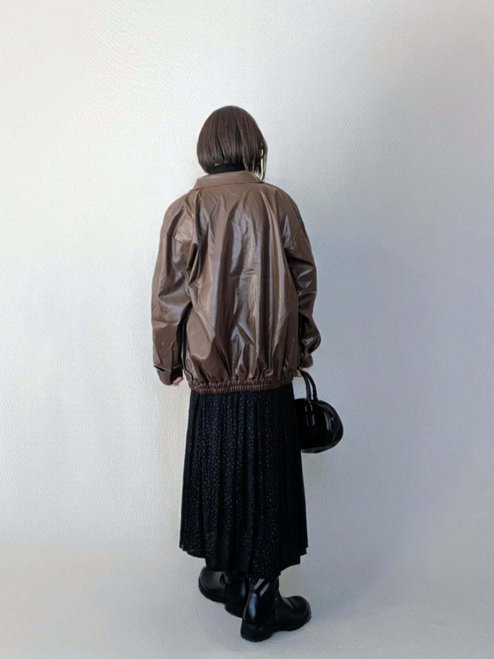 ブラウン系のブルゾン、ブラック系のスカート、ブラック系のブーツを着用したレディースの冬コーディネートの3枚目の写真