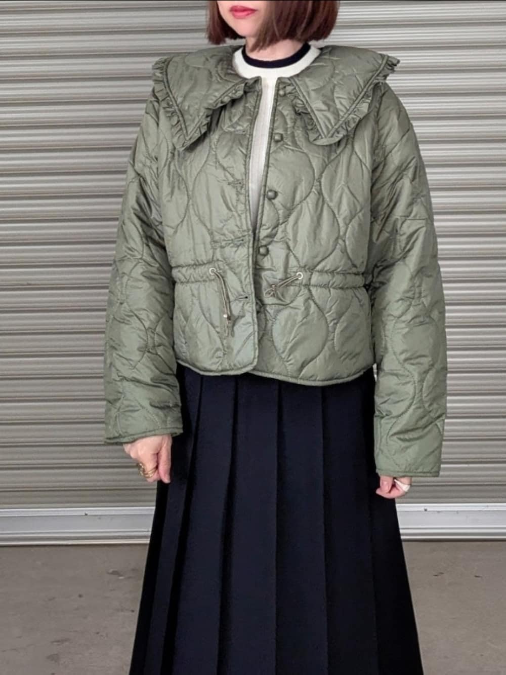 グリーン系のダウンジャケット/コート、ホワイト系のニット/セーター、ブラック系のブーツを着用したレディースの秋コーディネートの4枚目の写真