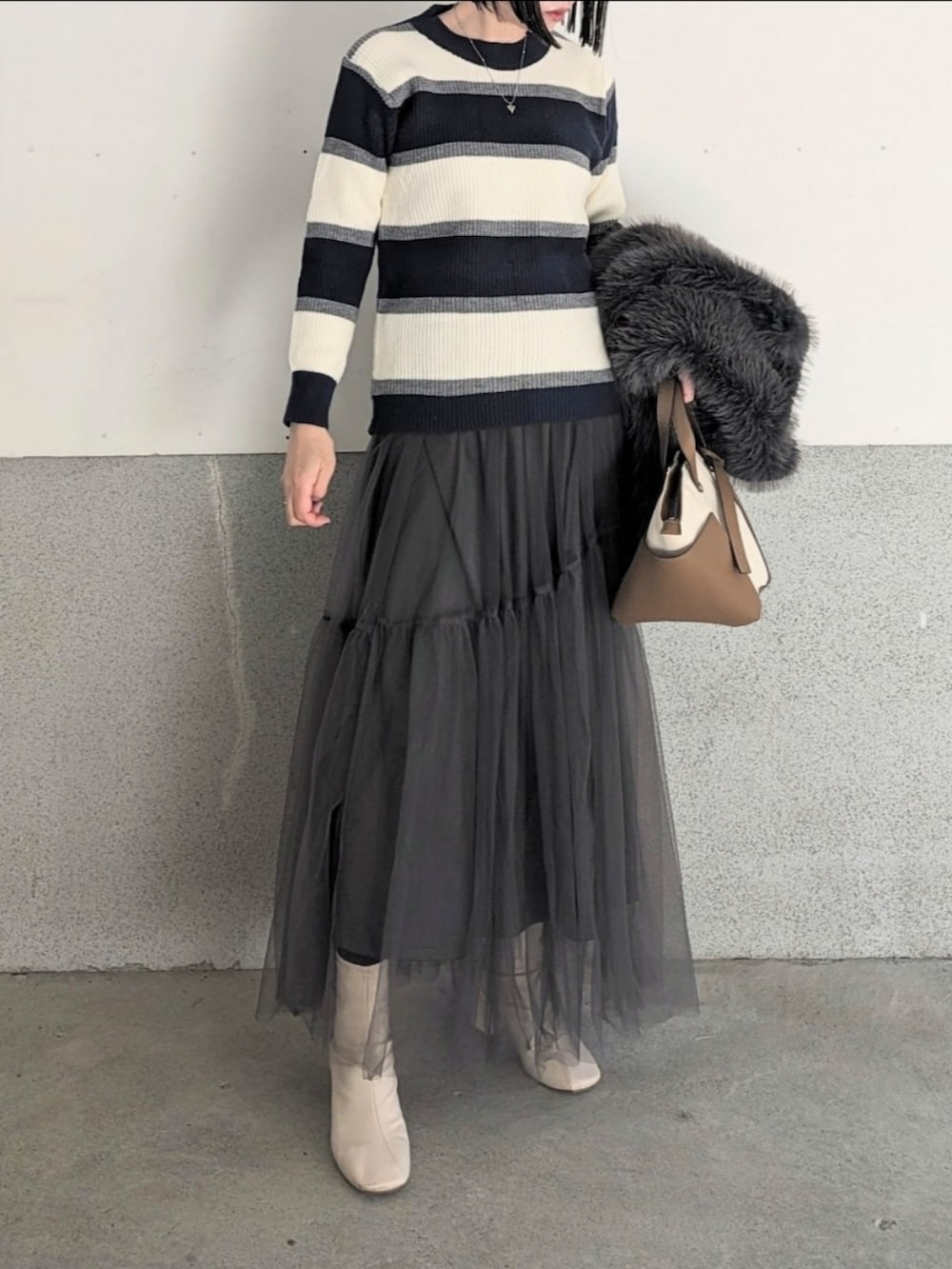 ブルー系のニット/セーター、グレー系のベスト、ブラウン系のトートバッグを着用したレディースの冬コーディネートの2枚目の写真