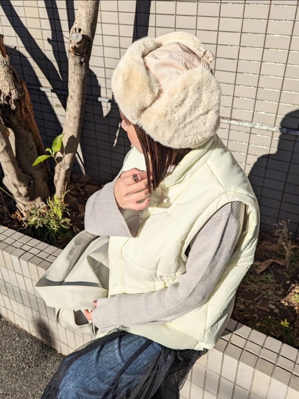 ホワイト系のダウンベスト、グレー系のショルダーバッグ、シルバー系のブーツを着用したレディースの冬コーディネートの2枚目の写真