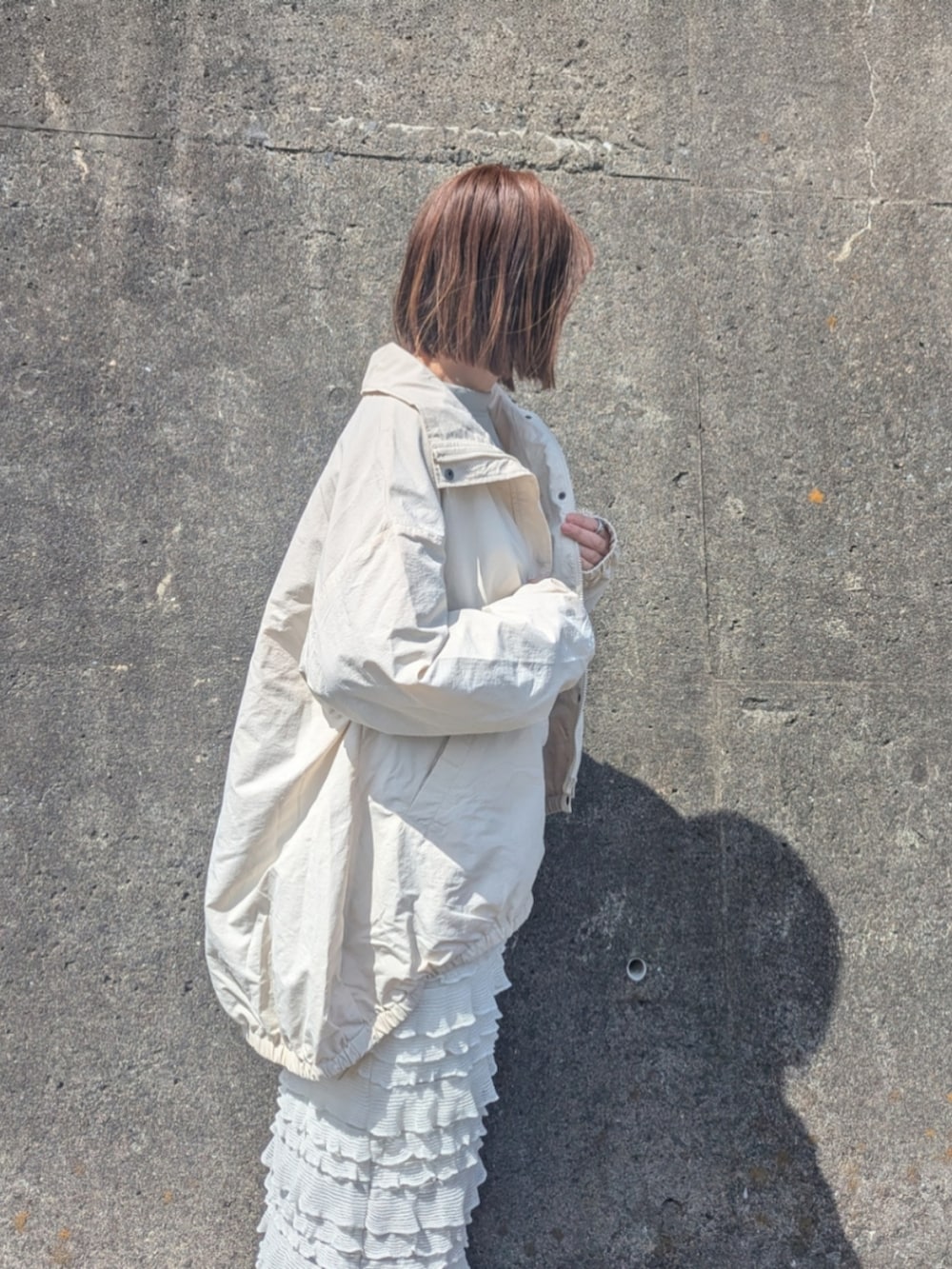 ホワイト系のナイロンジャケット、グリーン系のスウェット、ホワイト系のスカートを着用したレディースの春コーディネートの5枚目の写真