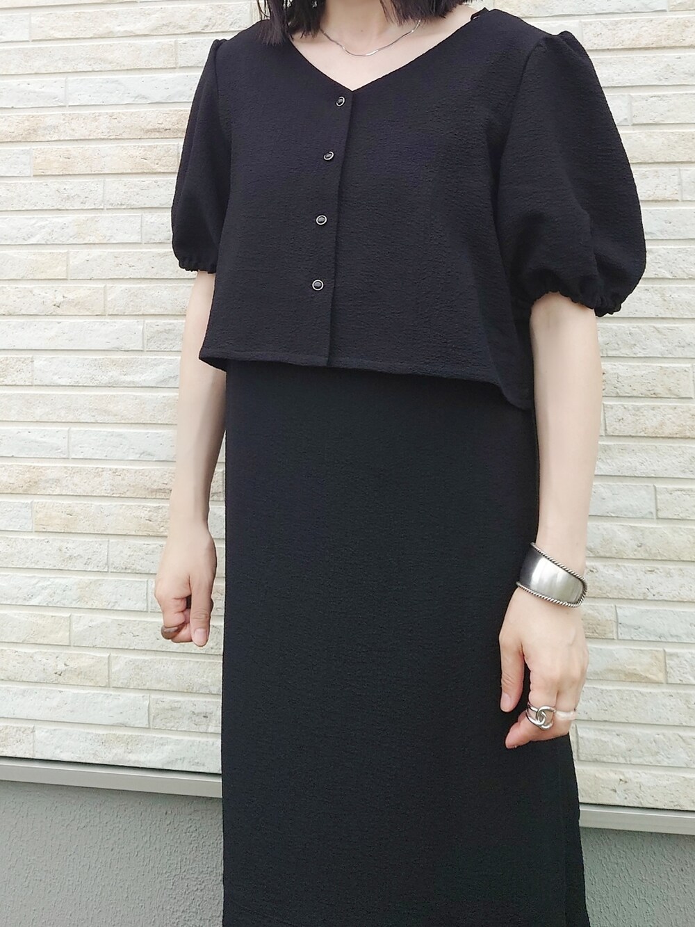 ブラック系のワンピース、ブラウン系のハンドバッグ、ベージュ系のサンダルを着用したレディースの夏コーディネートの3枚目の写真