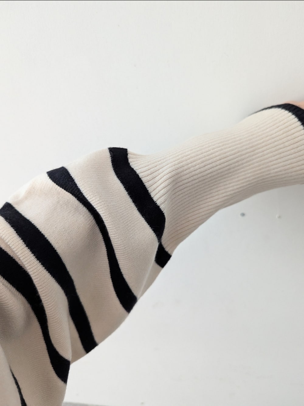 ホワイト系のニット/セーター、ブラック系のスカート、ベージュ系のノーカラーコートを着用したレディースの秋コーディネートの4枚目の写真