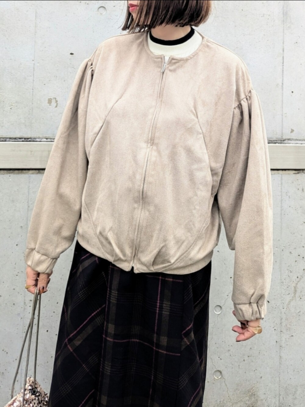 ベージュ系のブルゾン、ホワイト系のニット/セーター、ベージュ系のショルダーバッグを着用したレディースの秋コーディネートの3枚目の写真