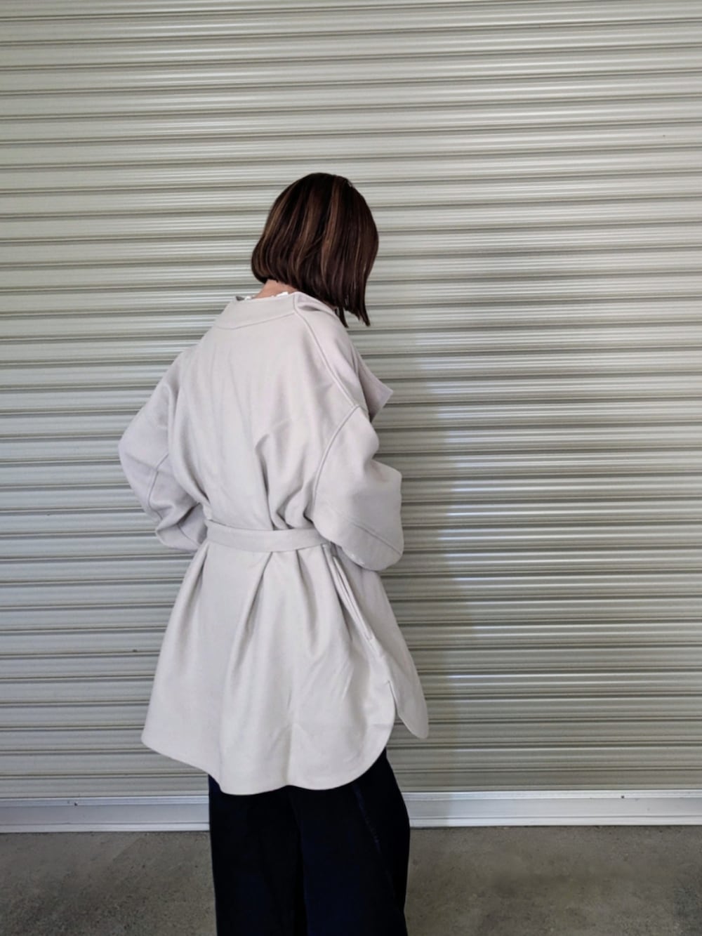 ベージュ系のノーカラーコート、ホワイト系のシャツ/ブラウス、ブラック系のベストを着用したレディースの秋コーディネートの4枚目の写真