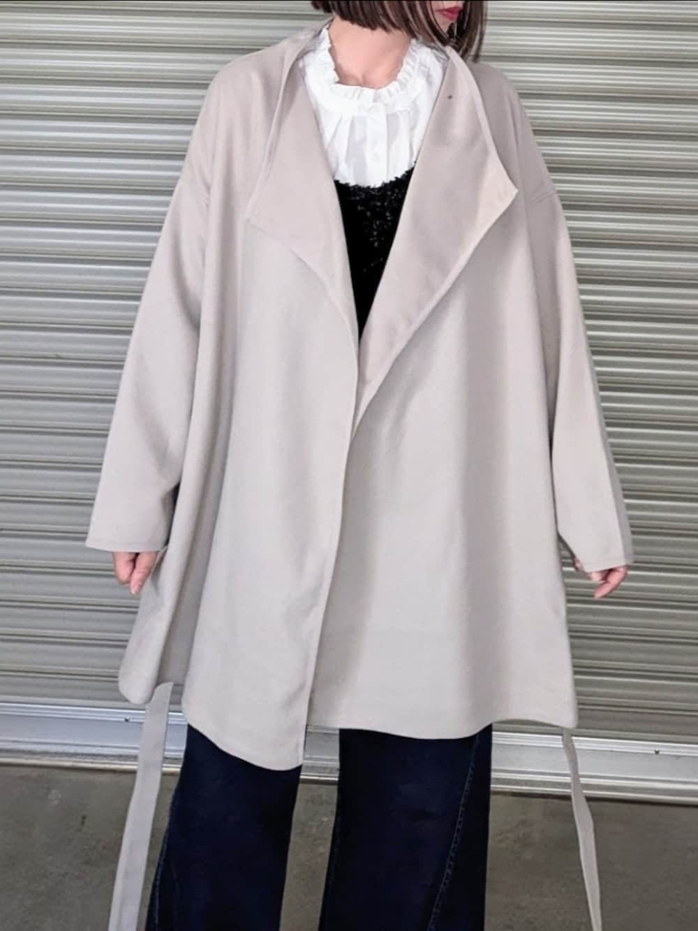 ベージュ系のノーカラーコート、ホワイト系のシャツ/ブラウス、ブラック系のベストを着用したレディースの秋コーディネートの2枚目の写真