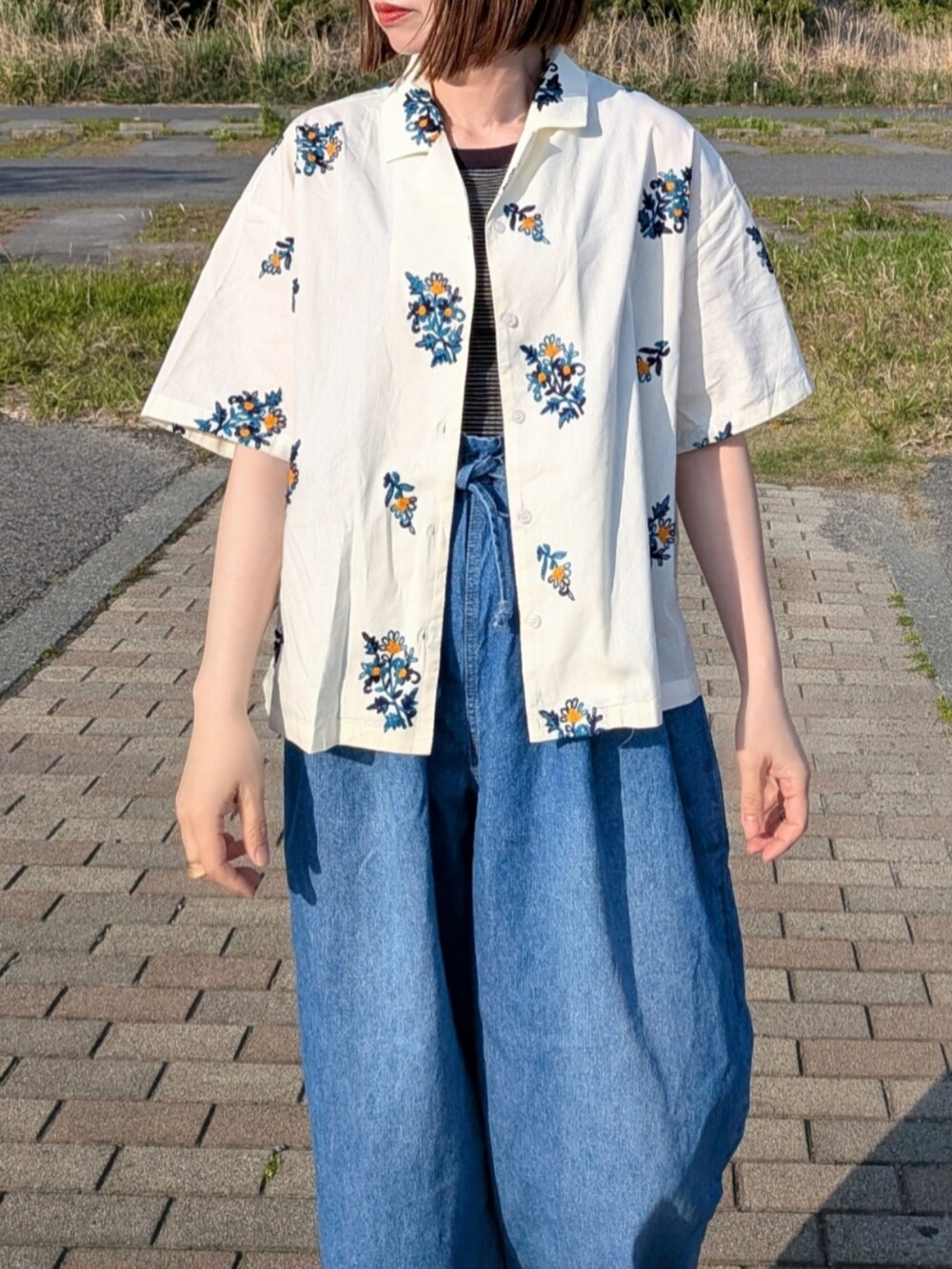 イエロー系のシャツ/ブラウス、ブルー系のデニムパンツ、ブラック系のタンクトップを着用したレディースの春コーディネートの3枚目の写真