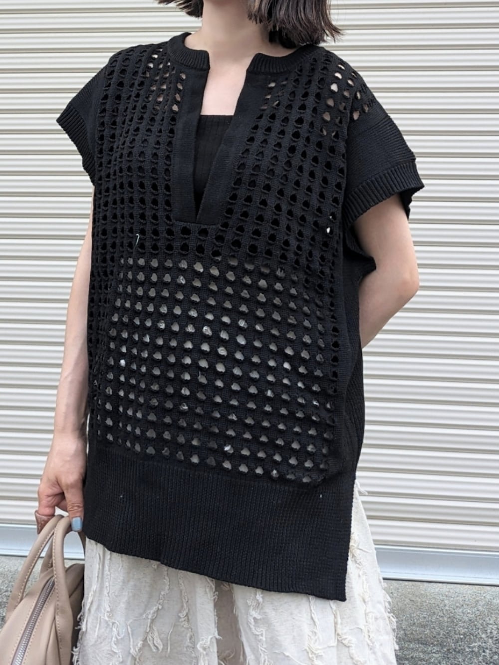 ブラック系のベスト、ホワイト系のスカート、ベージュ系のボストンバッグを着用したレディースの夏コーディネートの2枚目の写真