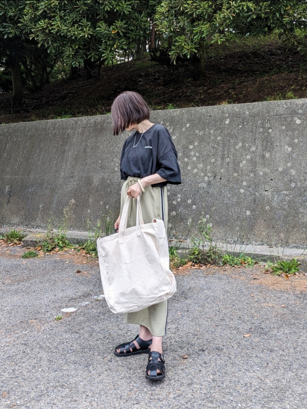 ブラック系のTシャツ/カットソー、ブルー系のスカート、ベージュ系のショルダーバッグを着用したレディースの春コーディネートの3枚目の写真