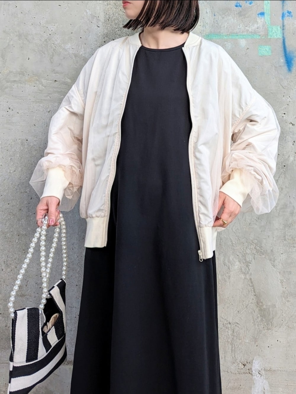 ホワイト系のブルゾン、ブラック系のワンピース、ホワイト系のショルダーバッグを着用したレディースの春コーディネートの3枚目の写真