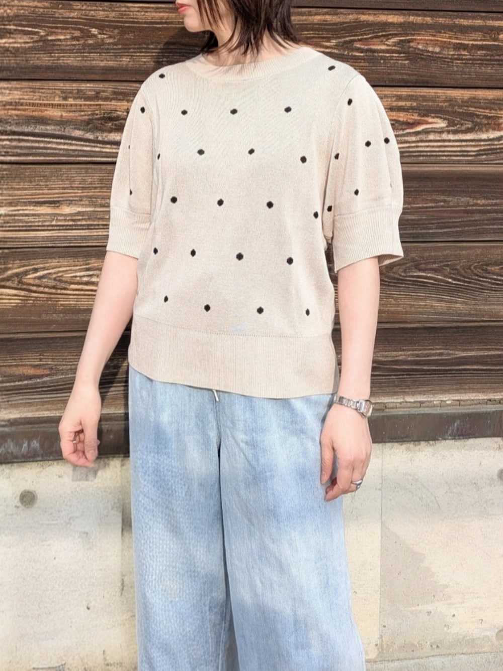 ベージュ系のニット/セーター、ブルー系のデニムパンツ、ホワイト系のショルダーバッグを着用したレディースの春コーディネートの3枚目の写真