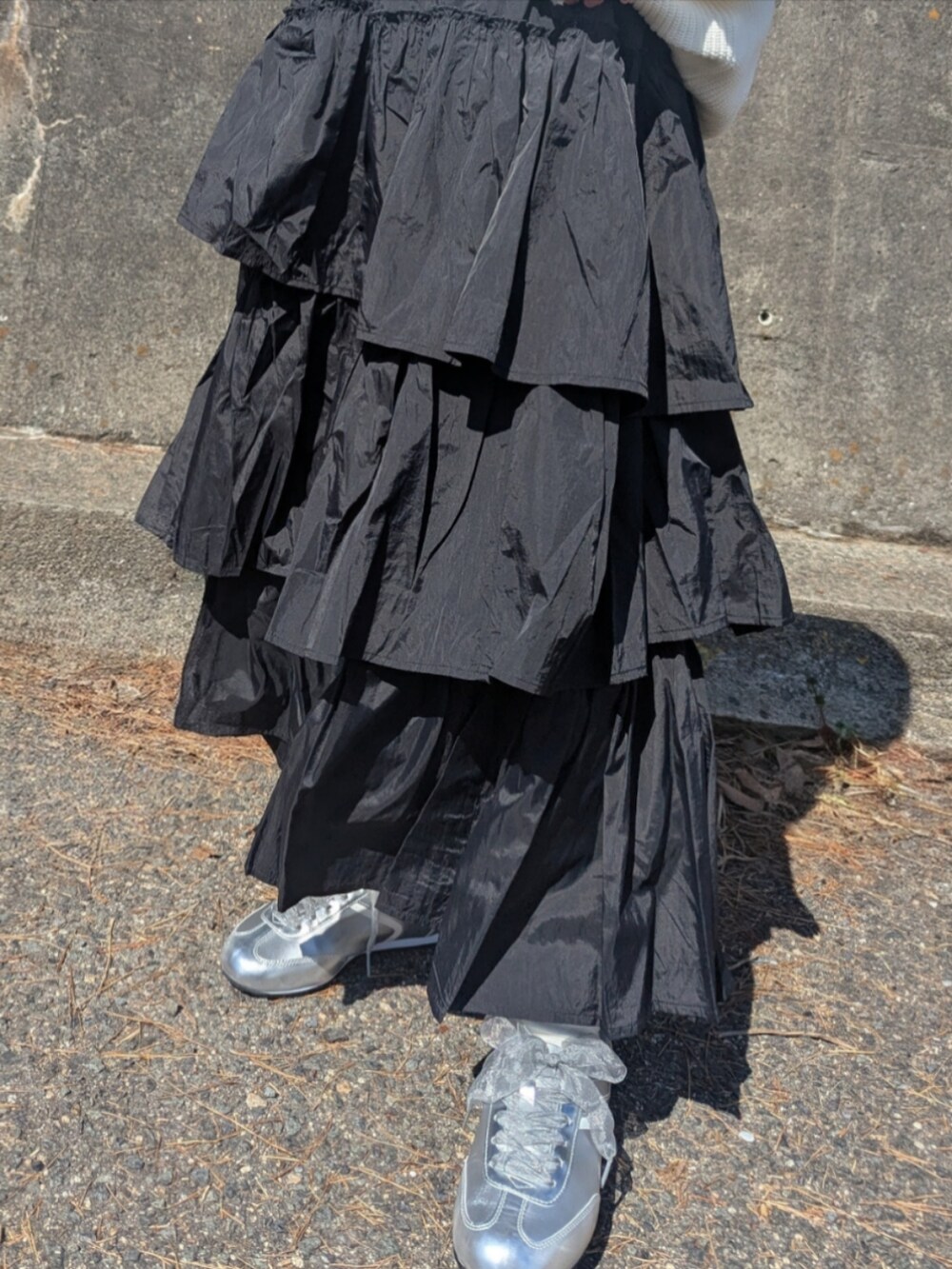 ホワイト系のニット/セーター、ブラック系のスカート、シルバー系のスニーカーを着用したレディースの春コーディネートの3枚目の写真