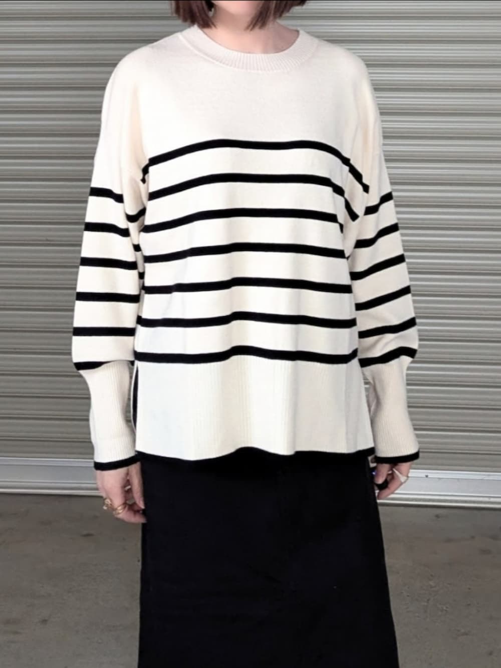 ホワイト系のニット/セーター、ブラック系のスカート、ベージュ系のノーカラーコートを着用したレディースの秋コーディネートの2枚目の写真