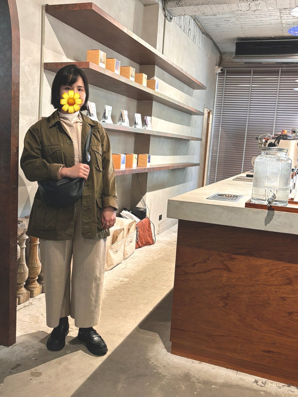 グリーン系のピーコート、ベージュ系のシャツ/ブラウス、ブラック系のショルダーバッグを着用したレディースの春コーディネートの2枚目の写真