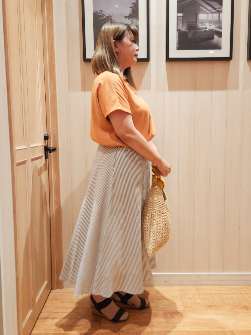 オレンジ系のシャツ/ブラウス、グレー系のスカート、イエロー系のトートバッグを着用したレディースの夏コーディネートの2枚目の写真