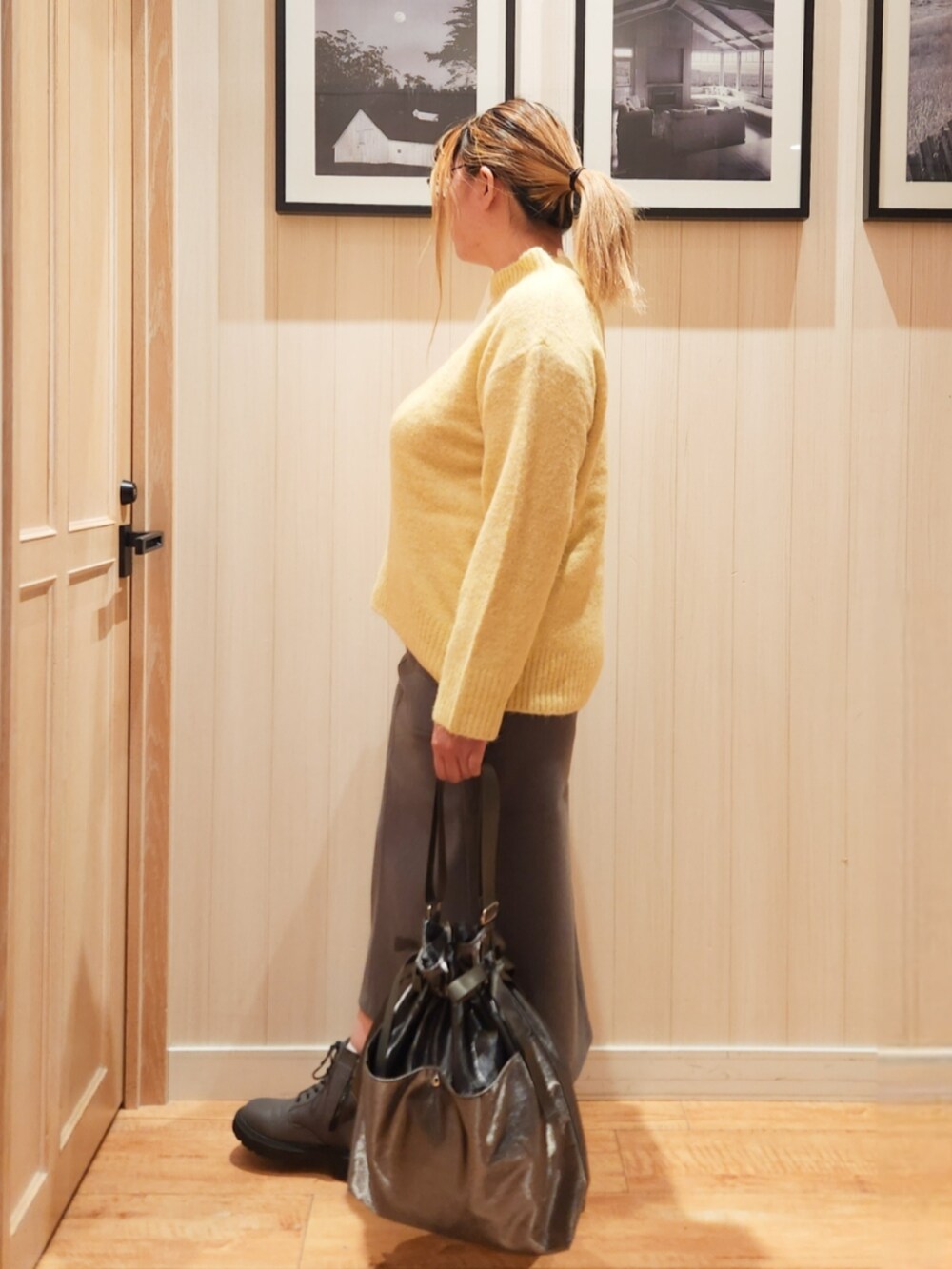 イエロー系のニット/セーター、グレー系のスカート、ブラック系のショルダーバッグを着用したレディースの秋コーディネートの3枚目の写真