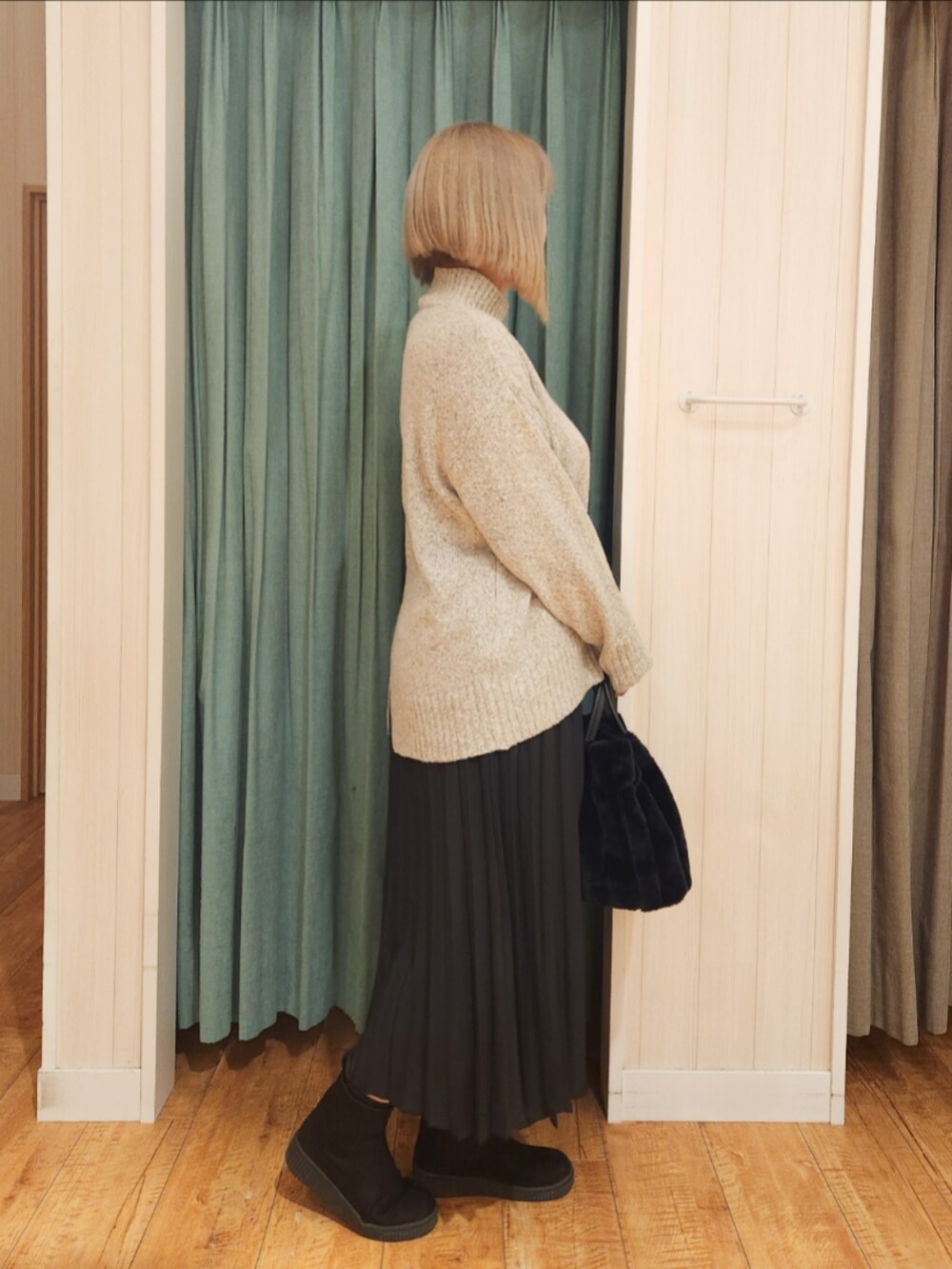 ベージュ系のニット/セーター、ブラック系のスカート、ブラック系のブーツを着用したレディースの冬コーディネートの2枚目の写真