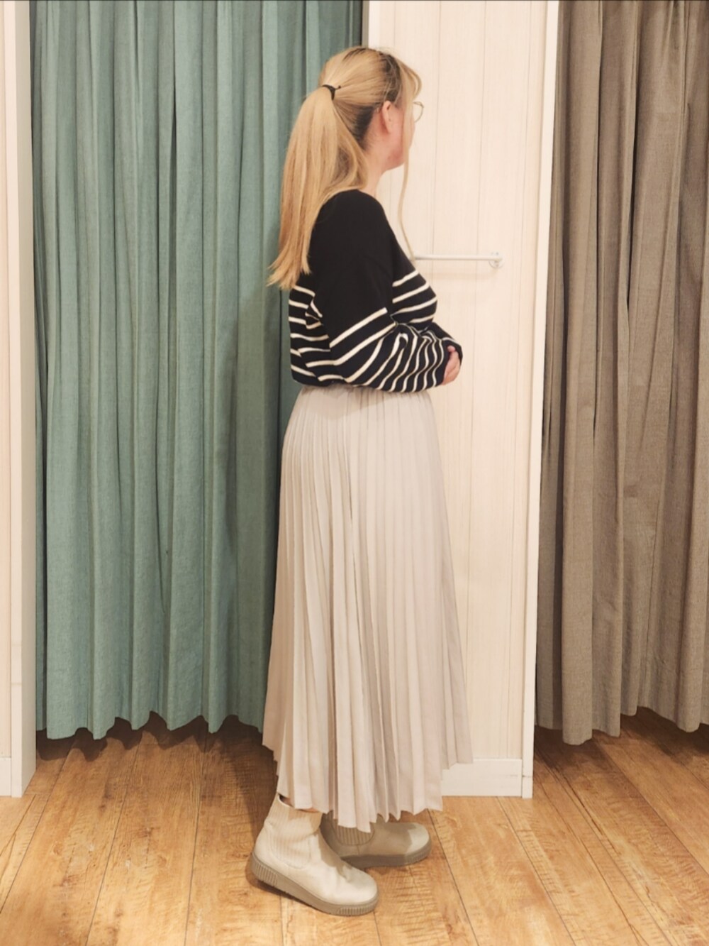 ブラック系のニット/セーター、ベージュ系のスカート、ホワイト系のブーツを着用したレディースの冬コーディネートの2枚目の写真