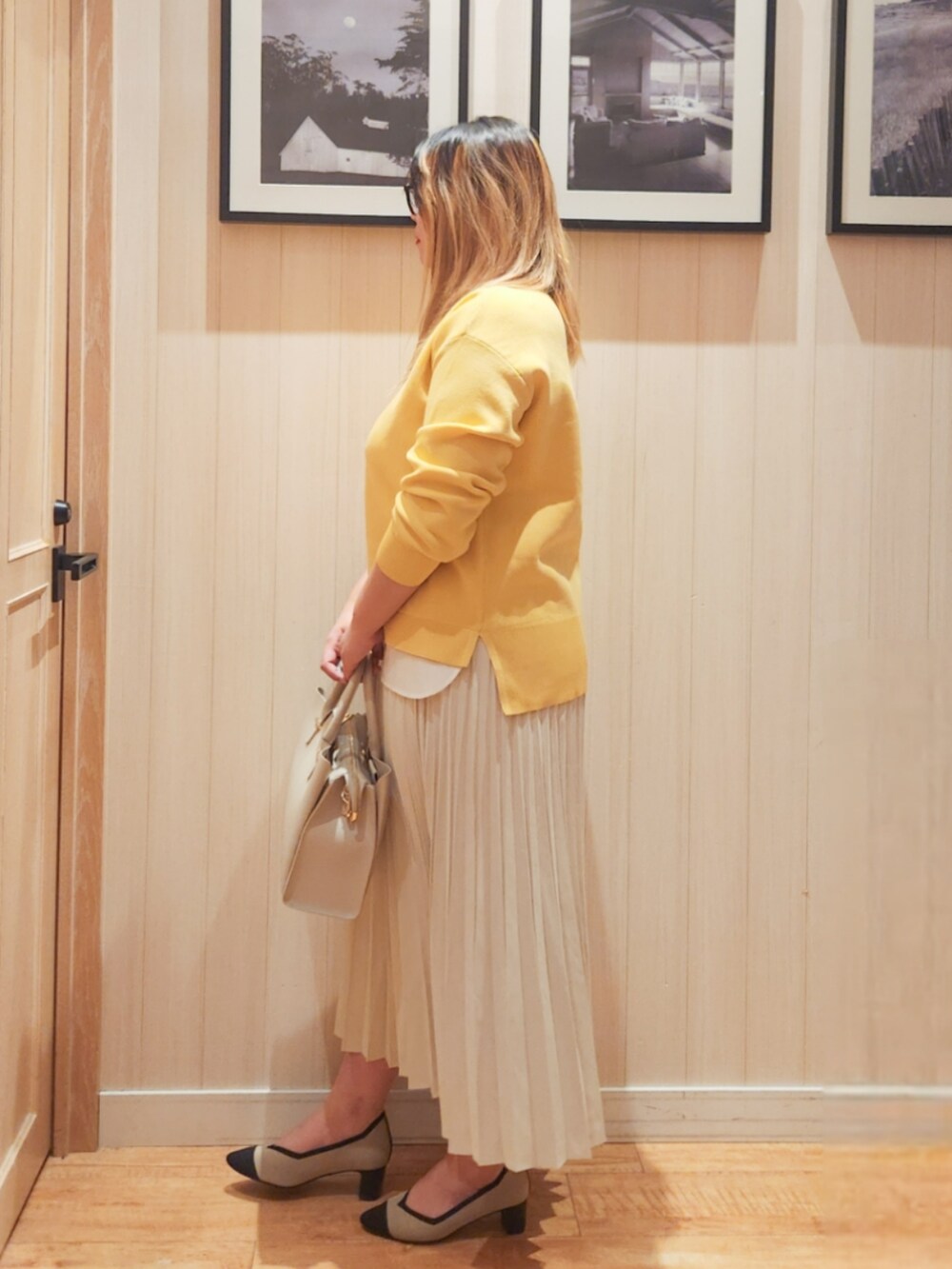 イエロー系のニット/セーター、ホワイト系のスカート、グレー系のトートバッグを着用したレディースの春コーディネートの2枚目の写真