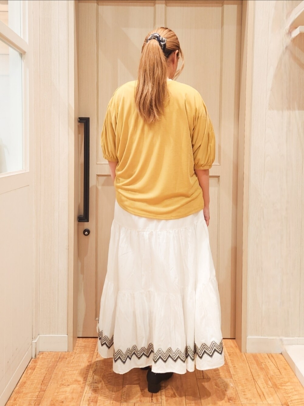 イエロー系のカーディガン/ボレロ、ホワイト系のTシャツ/カットソー、ホワイト系のスカートを着用したレディースの夏コーディネートの3枚目の写真