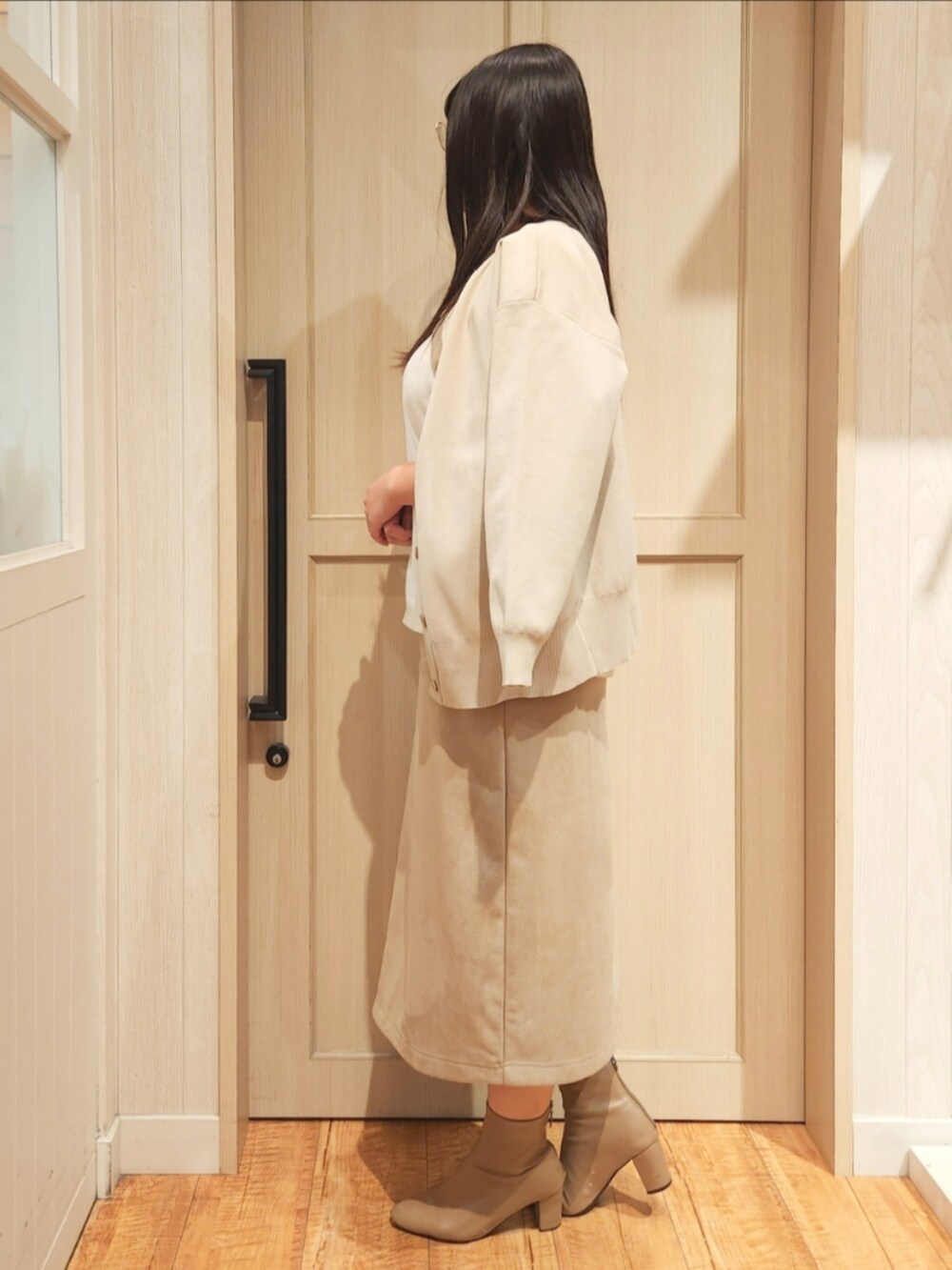 ホワイト系のカーディガン/ボレロ、ホワイト系のTシャツ/カットソー、ベージュ系のスカートを着用したレディースの冬コーディネートの2枚目の写真