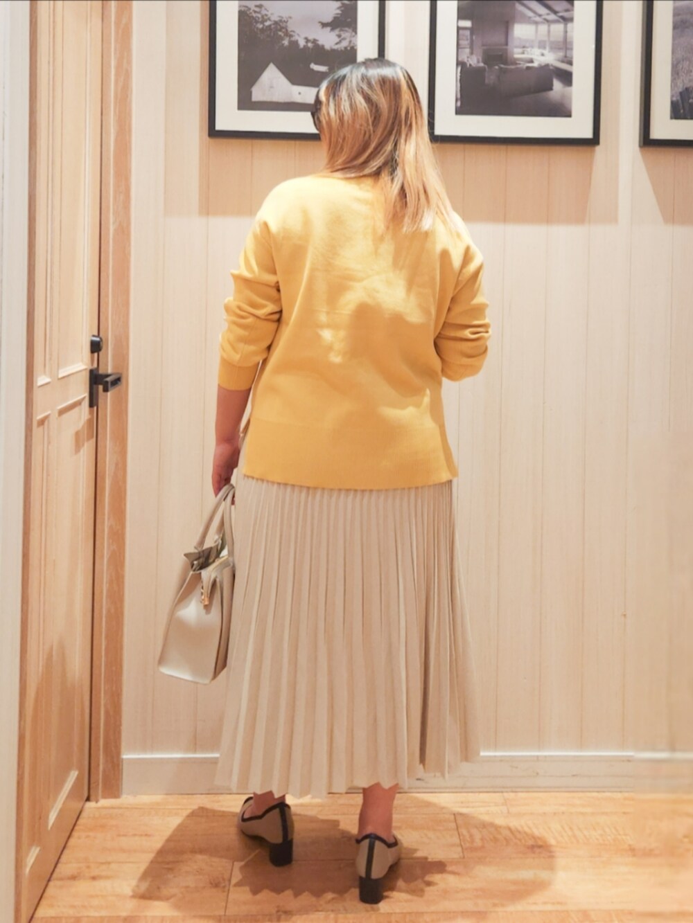イエロー系のニット/セーター、ホワイト系のスカート、グレー系のトートバッグを着用したレディースの春コーディネートの3枚目の写真