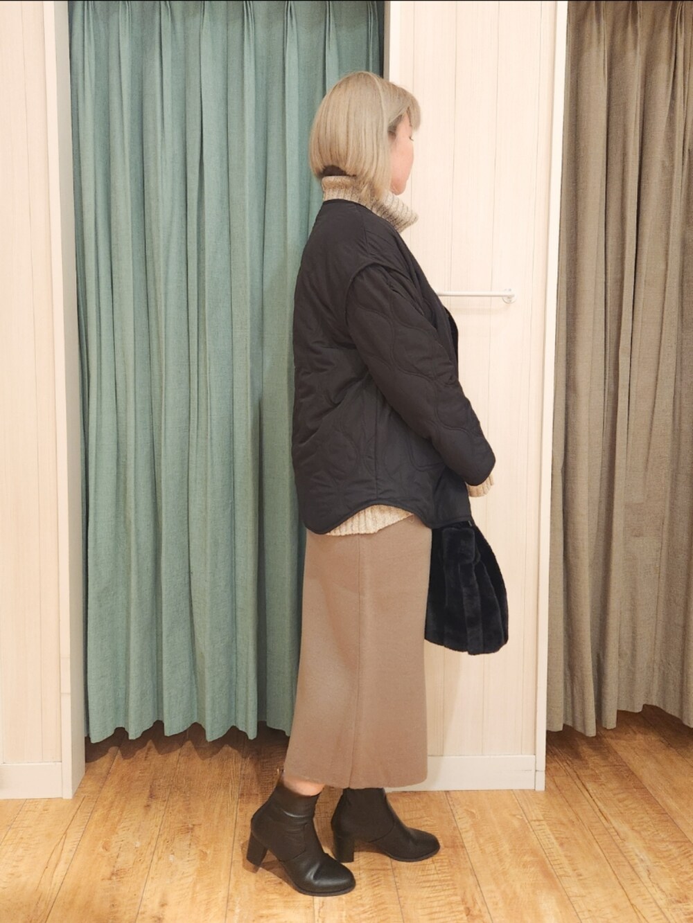 ブラック系のその他アウター、ベージュ系のニット/セーター、ブラウン系のスカートを着用したレディースの冬コーディネートの2枚目の写真