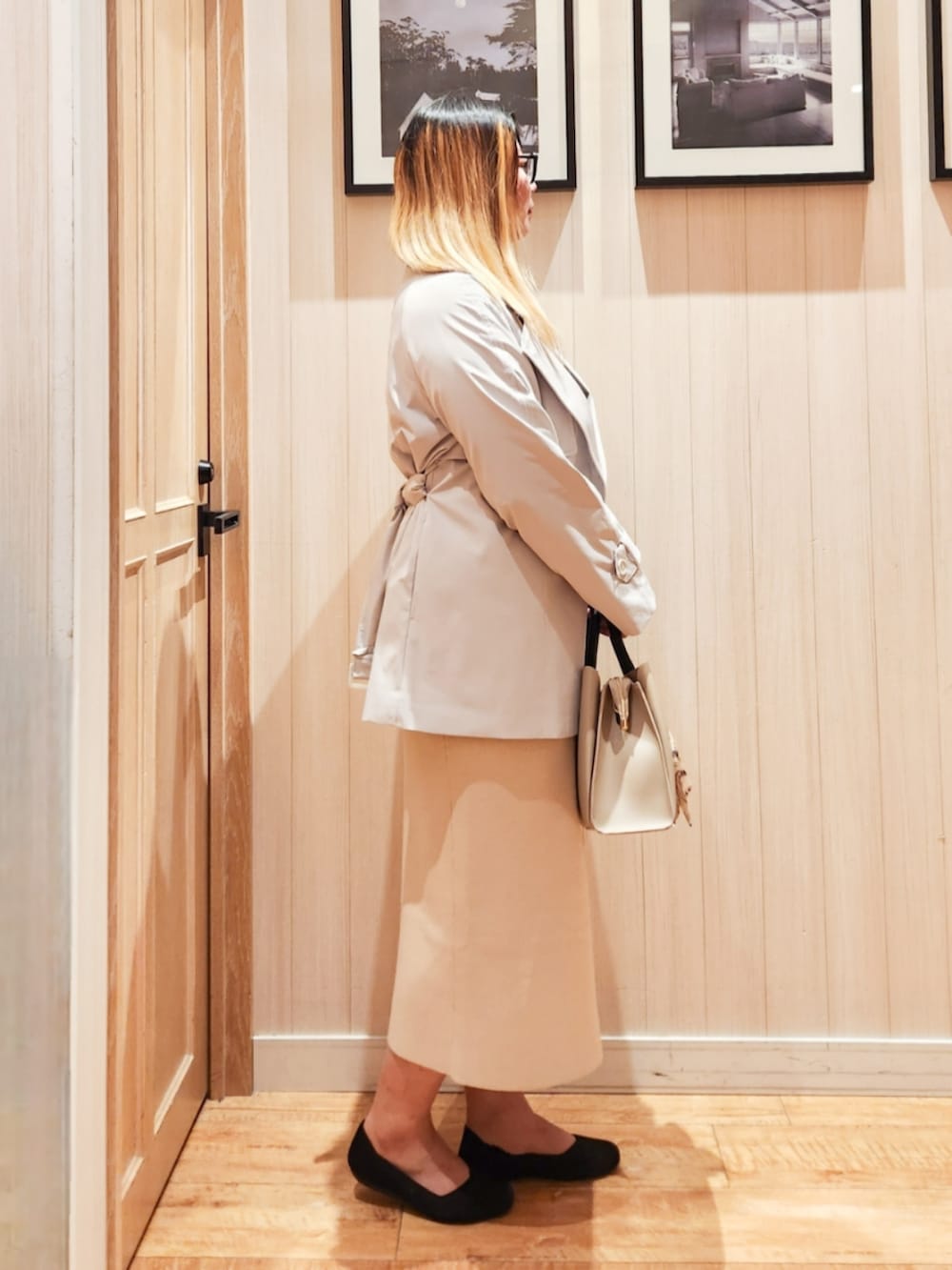 グレー系のトレンチコート、ブラック系のニット/セーター、ベージュ系のスカートを着用したレディースの冬コーディネートの2枚目の写真