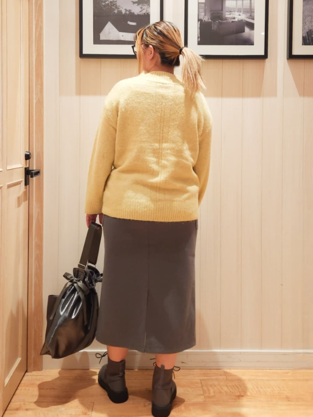イエロー系のニット/セーター、グレー系のスカート、ブラック系のショルダーバッグを着用したレディースの秋コーディネートの2枚目の写真
