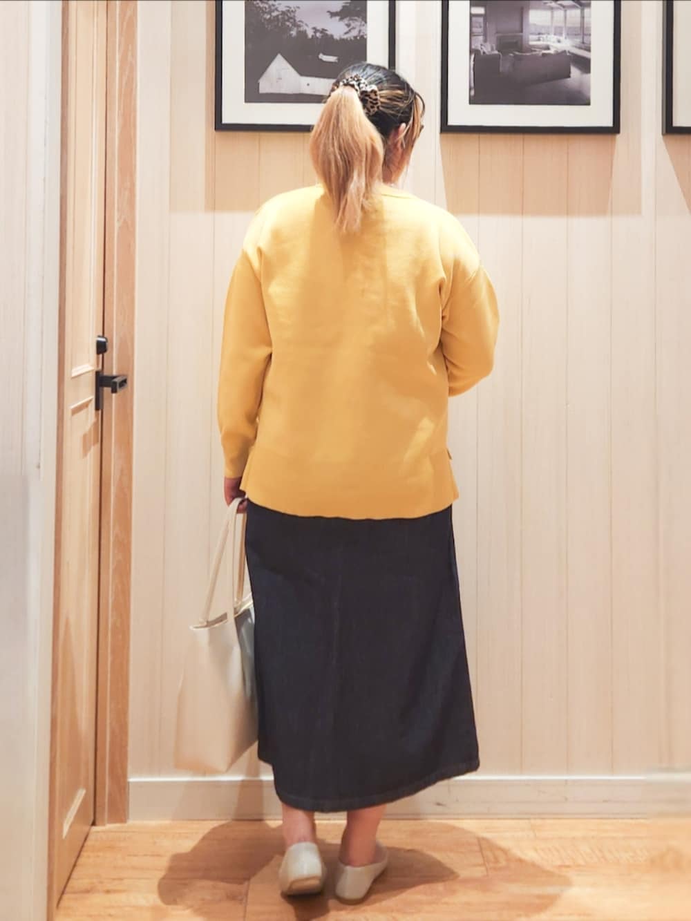 イエロー系のニット/セーター、ブルー系のデニムスカート、ベージュ系のパンプスを着用したレディースの春コーディネートの3枚目の写真