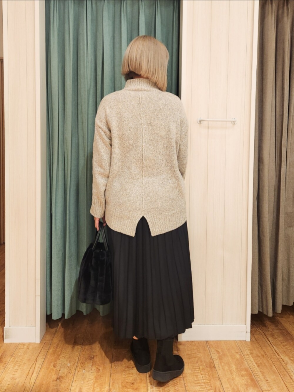 ベージュ系のニット/セーター、ブラック系のスカート、ブラック系のブーツを着用したレディースの冬コーディネートの3枚目の写真