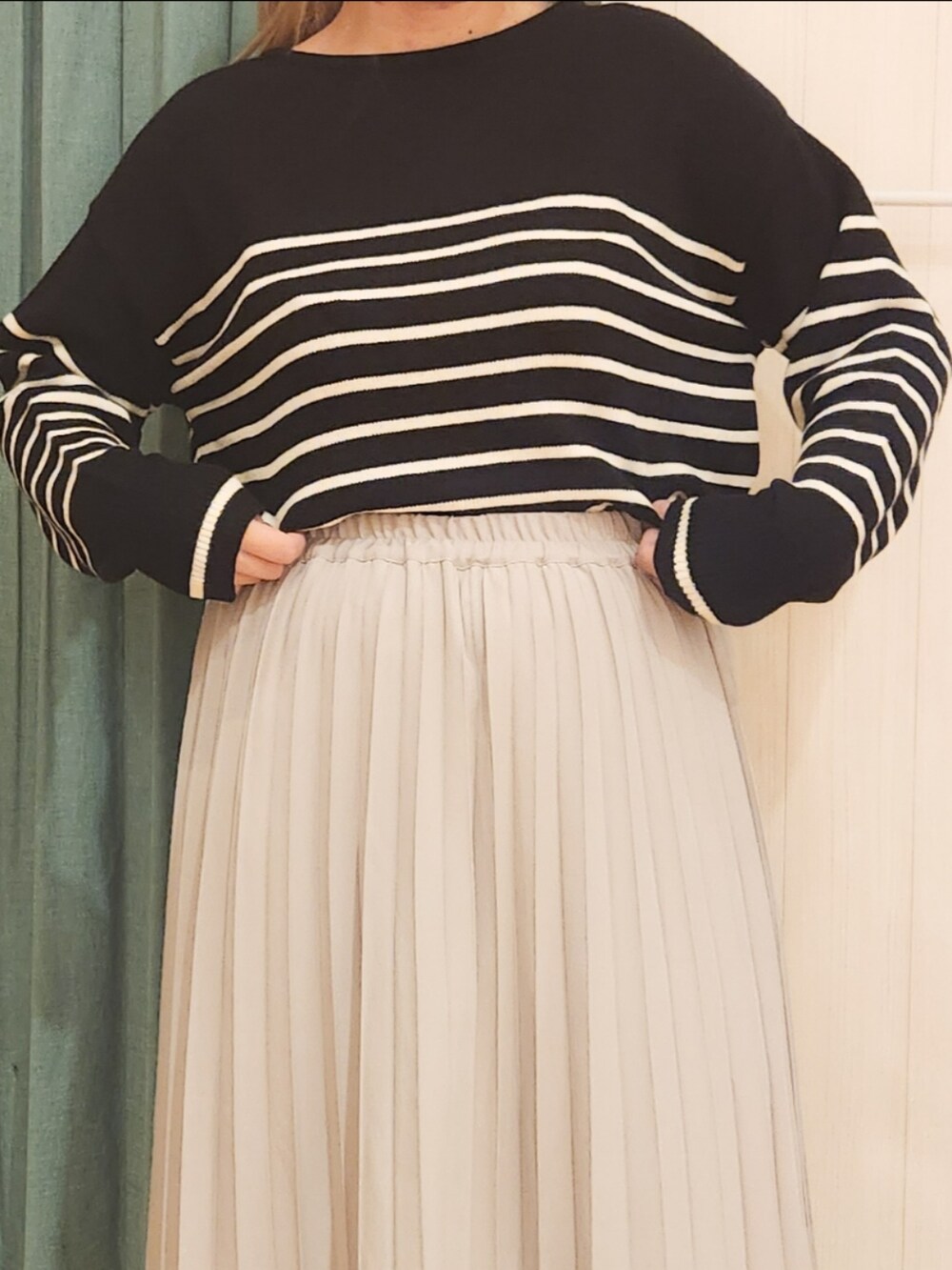 ブラック系のニット/セーター、ベージュ系のスカート、ホワイト系のブーツを着用したレディースの冬コーディネートの4枚目の写真