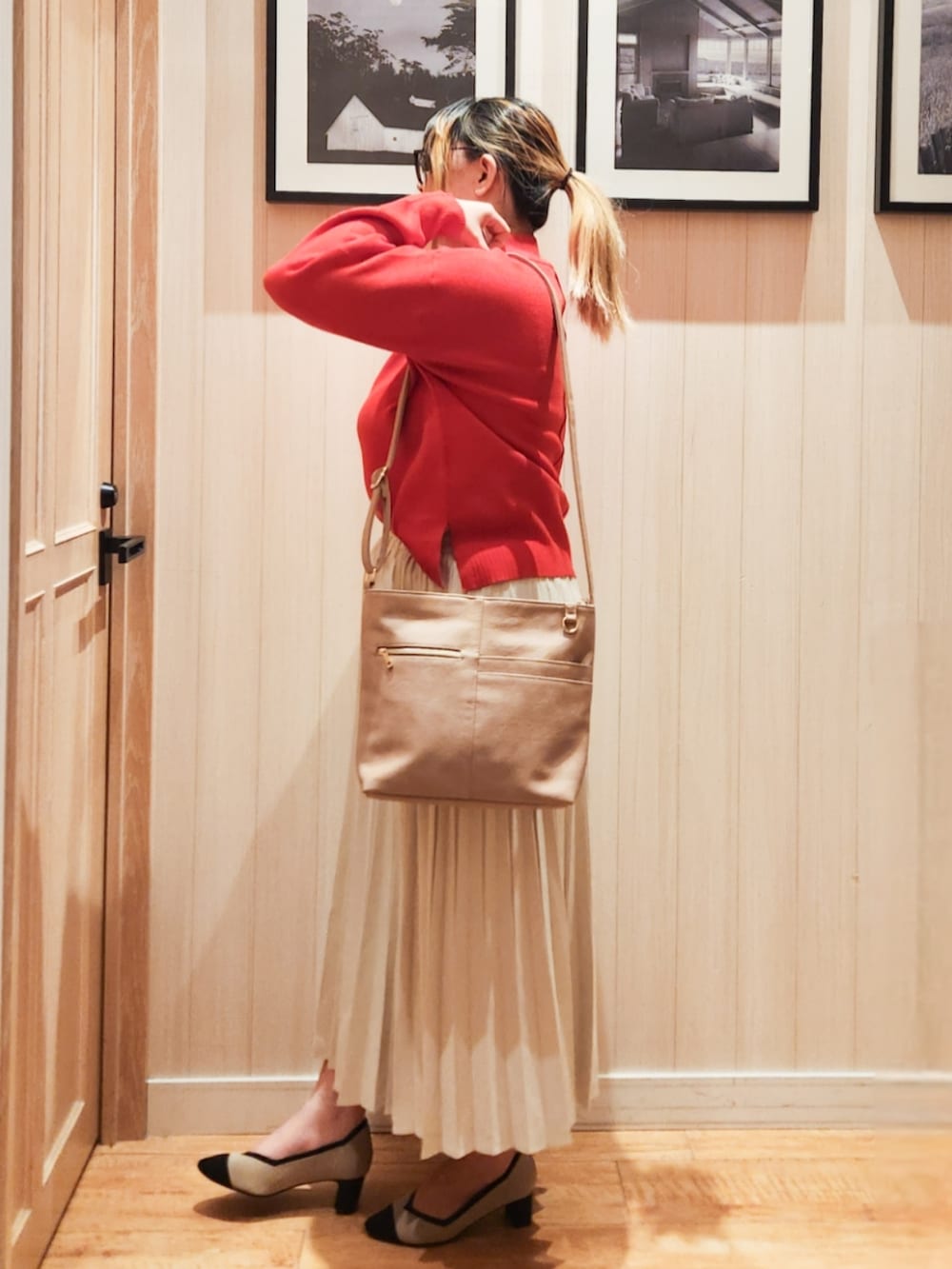 オレンジ系のニット/セーター、ホワイト系のスカート、ベージュ系のショルダーバッグを着用したレディースの冬コーディネートの2枚目の写真