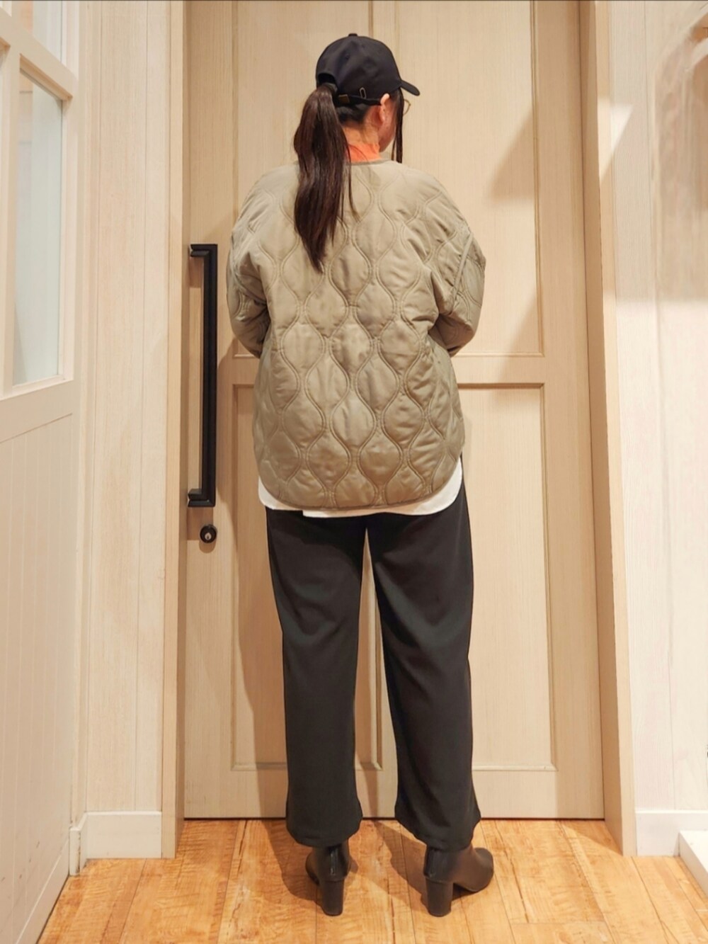 グリーン系のその他アウター、オレンジ系のニット/セーター、ブラック系のその他パンツを着用したレディースの冬コーディネートの3枚目の写真