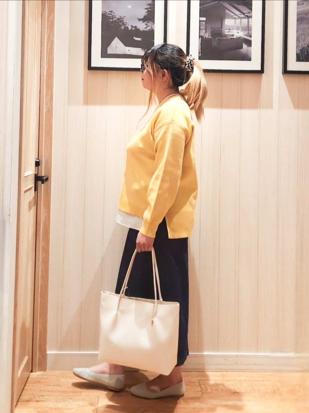 イエロー系のニット/セーター、ブルー系のデニムスカート、ベージュ系のパンプスを着用したレディースの春コーディネートの2枚目の写真