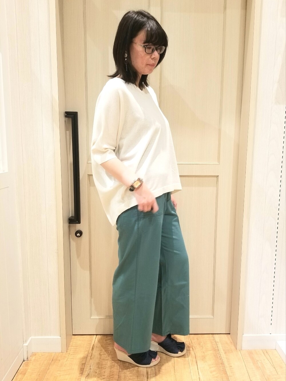 ホワイト系のニット/セーター、グリーン系のその他パンツ、ブルー系のサンダルを着用したレディースの春コーディネートの2枚目の写真