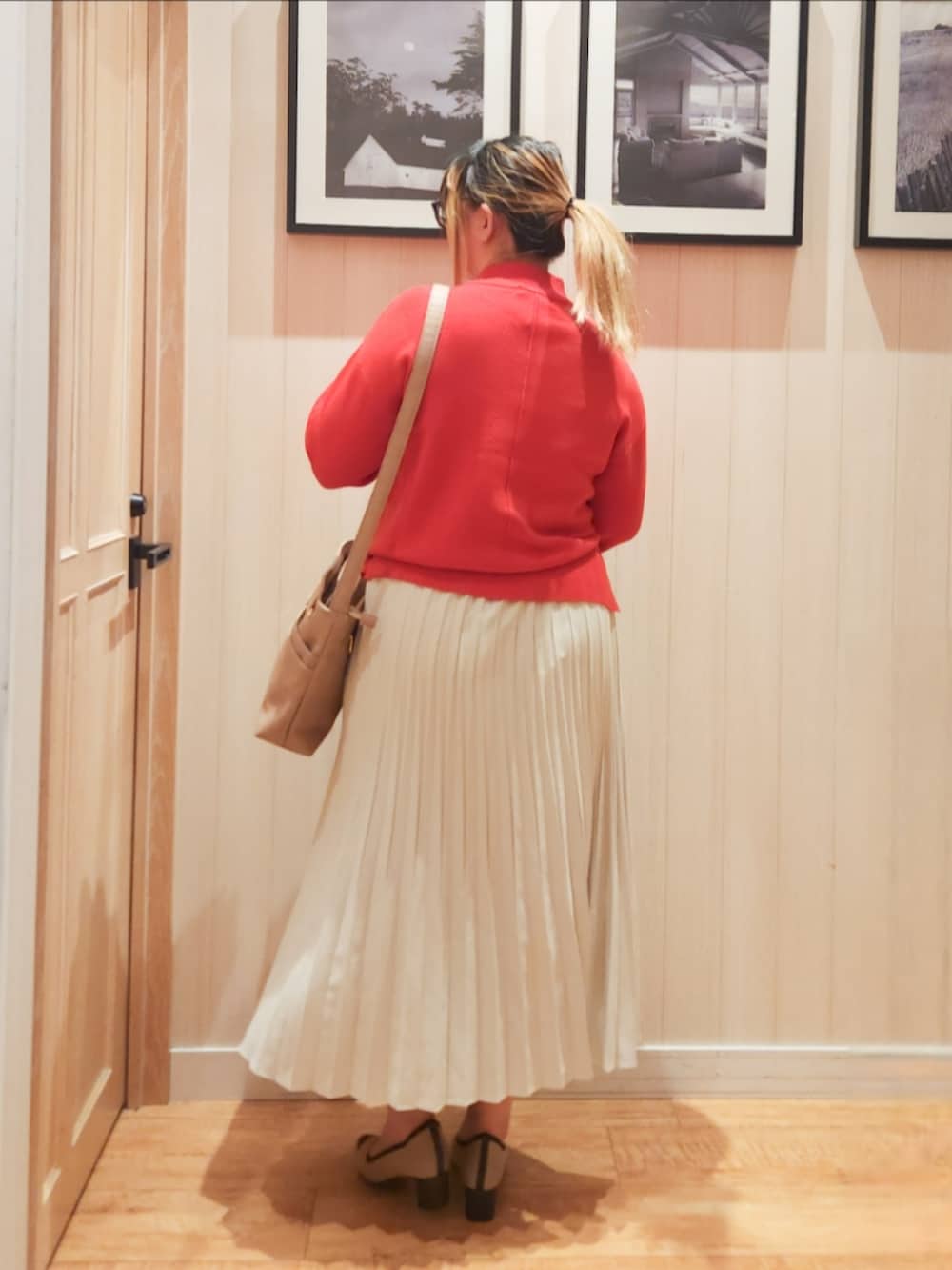 オレンジ系のニット/セーター、ホワイト系のスカート、ベージュ系のショルダーバッグを着用したレディースの冬コーディネートの3枚目の写真