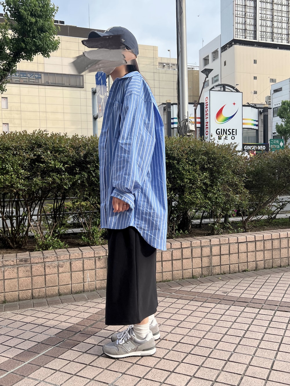 ブルー系のシャツ/ブラウス、グレー系のスニーカー、ブルー系のキャップを着用したレディースの春コーディネートの2枚目の写真