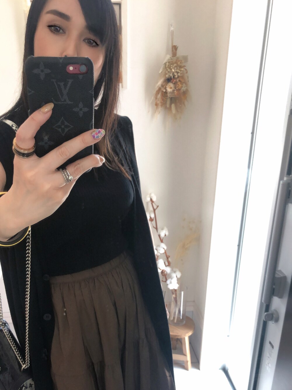 ブラック系のタンクトップ、ブラック系のショルダーバッグ、ブラウン系のスカートを着用したレディースの夏コーディネートの2枚目の写真