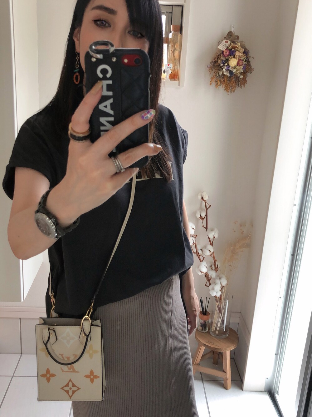 グレー系のトップス、ベージュ系のショルダーバッグ、グレー系のスカートを着用したレディースの夏コーディネートの2枚目の写真