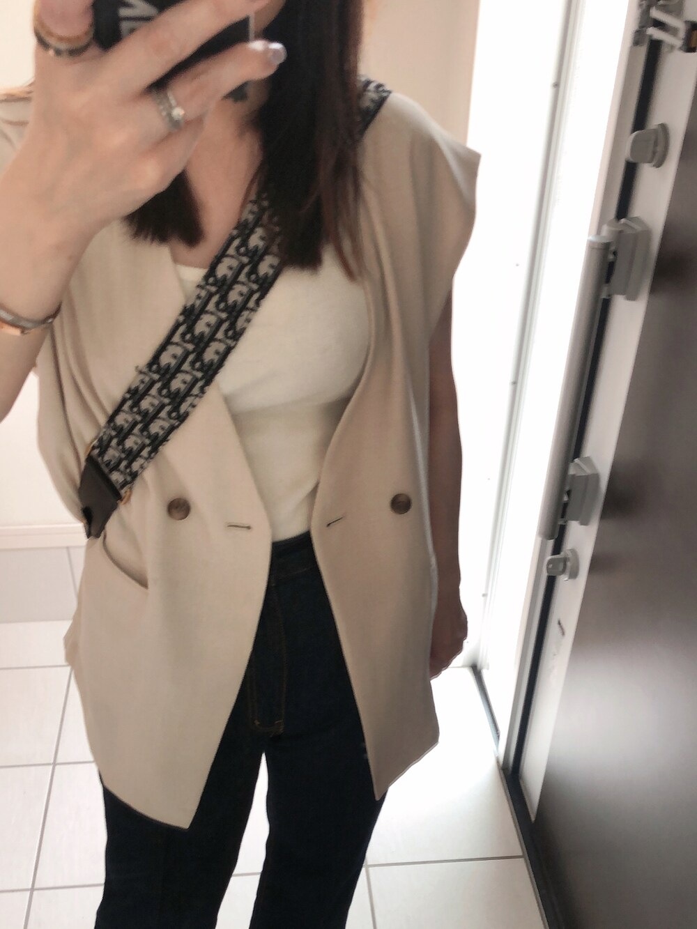 ホワイト系のタンクトップ、ホワイト系のベスト、ブラック系のショルダーバッグを着用したレディースの夏コーディネートの2枚目の写真