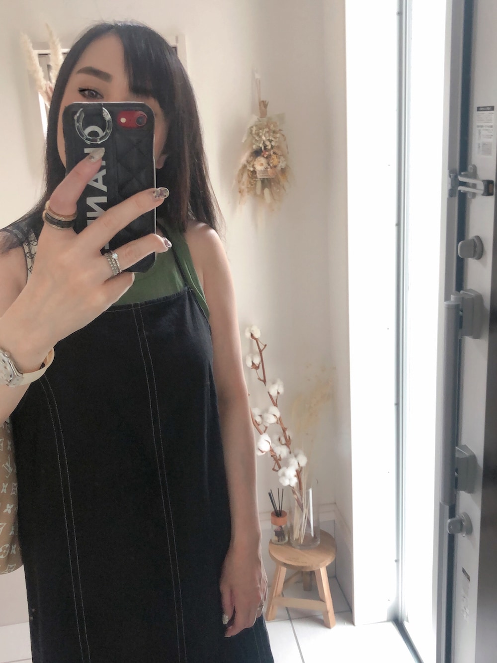 グリーン系のトートバッグ、グリーン系のトップス、ブラック系のワンピースを着用したレディースの夏コーディネートの2枚目の写真