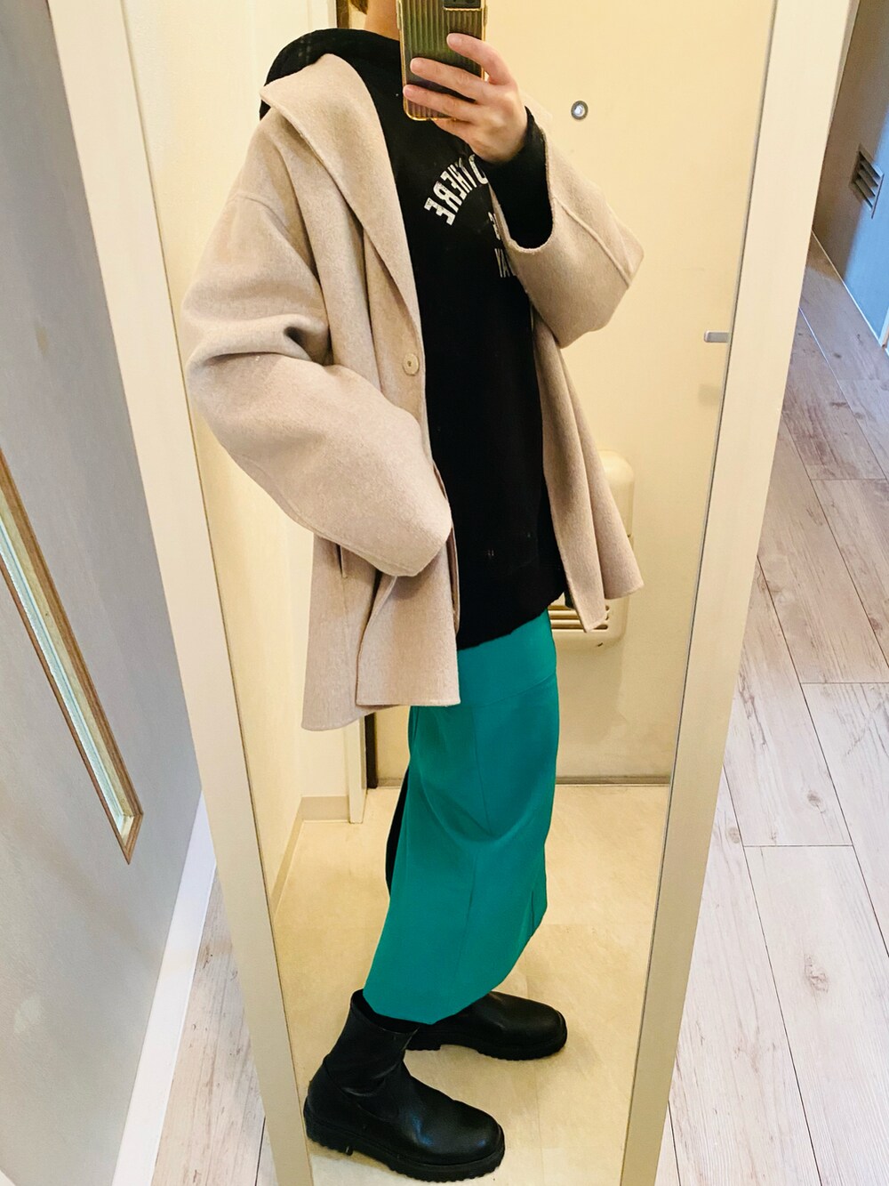 ブラック系のパーカー、グリーン系のスカート、ブラック系のブーツを着用したレディースの冬コーディネートの4枚目の写真