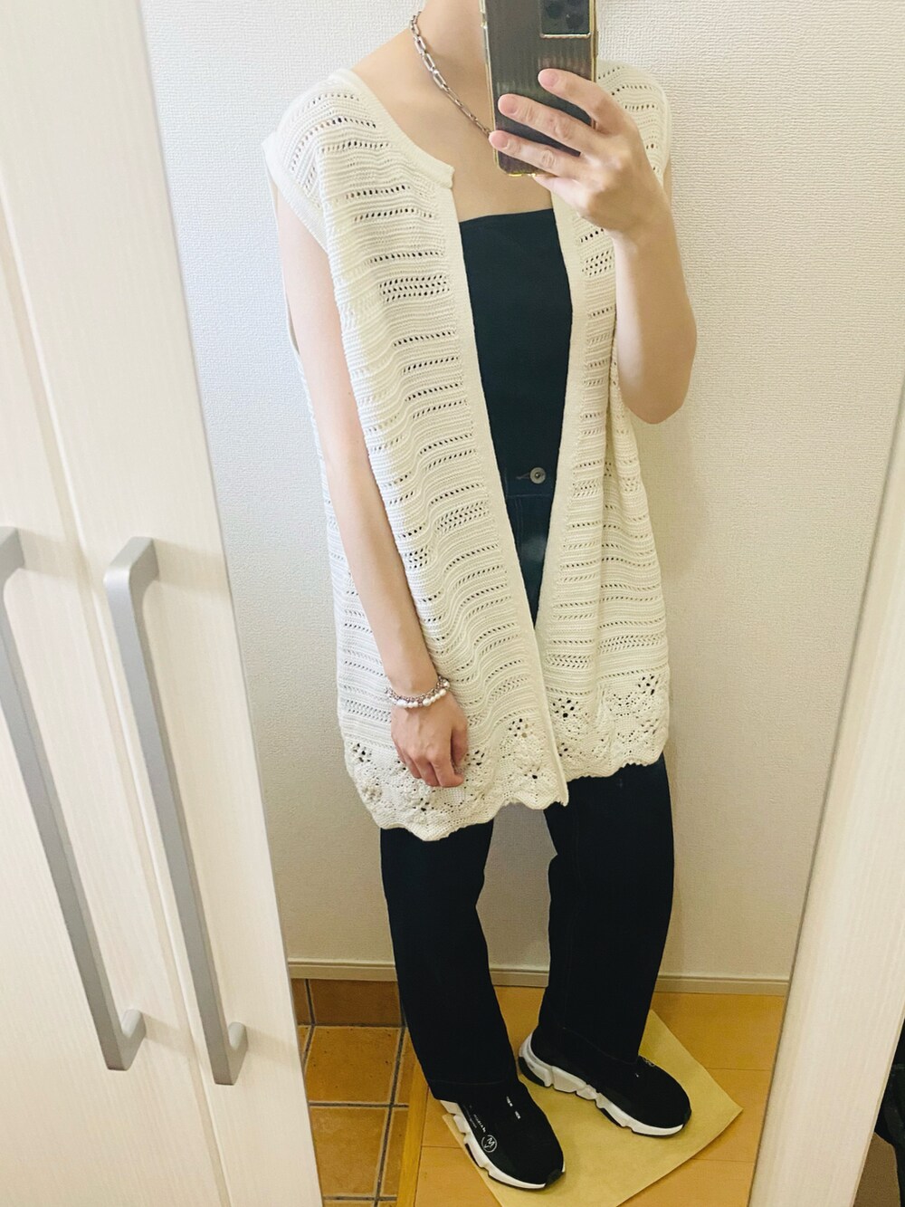 ブラック系のタンクトップ、ブルー系のデニムパンツ、ホワイト系のベストを着用したレディースの春コーディネートの2枚目の写真