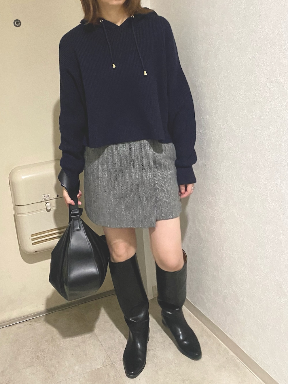 ブラック系のトートバッグ、ブルー系のパーカー、ブラック系のブーツを着用したレディースの秋コーディネートの2枚目の写真