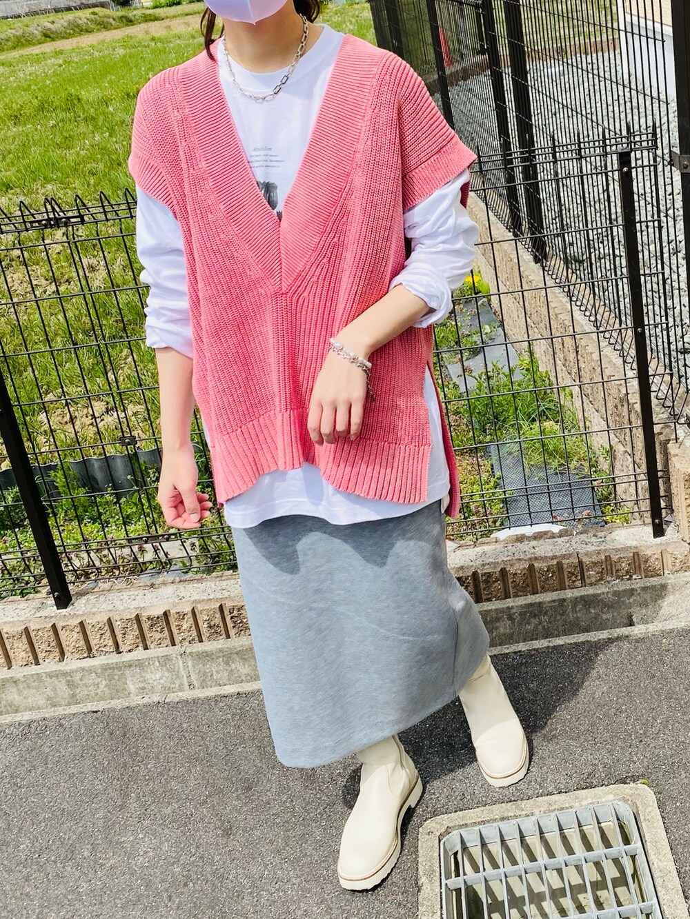 ピンク系のベスト、ホワイト系のTシャツ/カットソー、ベージュ系のステンカラーコートを着用したレディースの春コーディネートの4枚目の写真