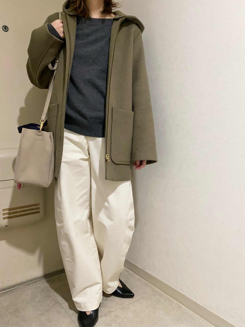 グレー系のニット/セーター、ホワイト系のパンツ、ブルー系のトートバッグを着用したレディースの冬コーディネートの2枚目の写真