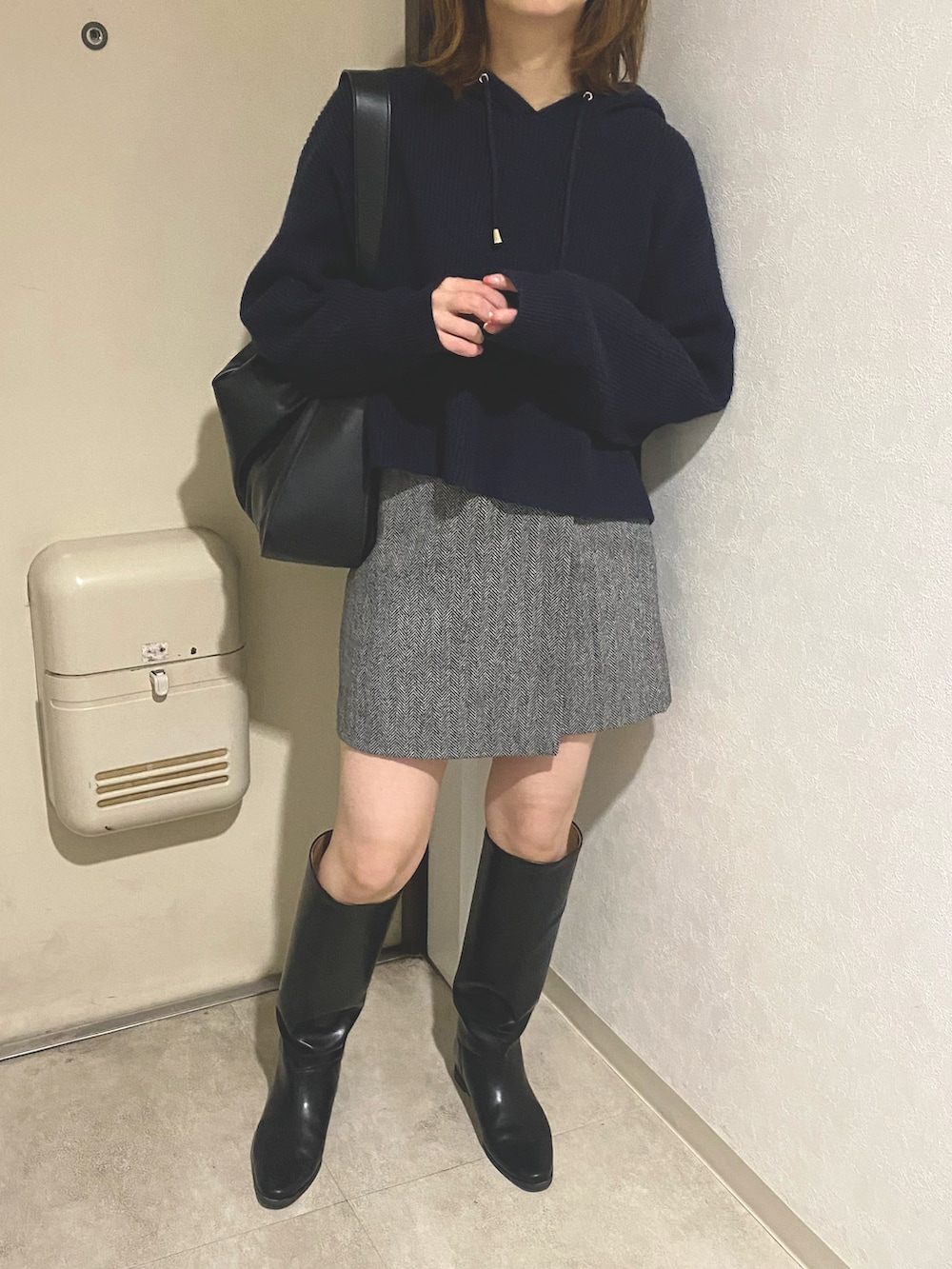 ブラック系のトートバッグ、ブルー系のパーカー、ブラック系のブーツを着用したレディースの秋コーディネートの3枚目の写真