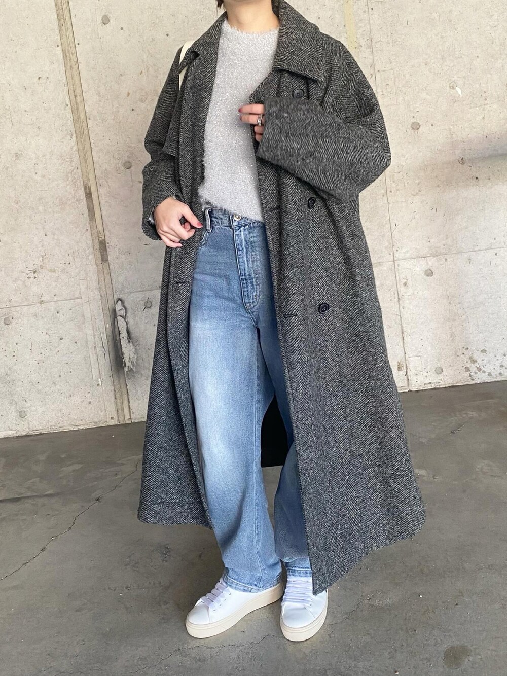 ホワイト系のスニーカー、ブルー系のデニムパンツ、グレー系のニット/セーターを着用したレディースの冬コーディネートの2枚目の写真