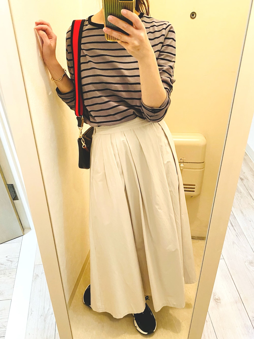 グレー系のTシャツ/カットソー、ベージュ系のスカート、ブラック系のスニーカーを着用したレディースの秋コーディネートの3枚目の写真